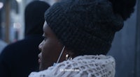 a woman wearing a beanie and listening to earphones